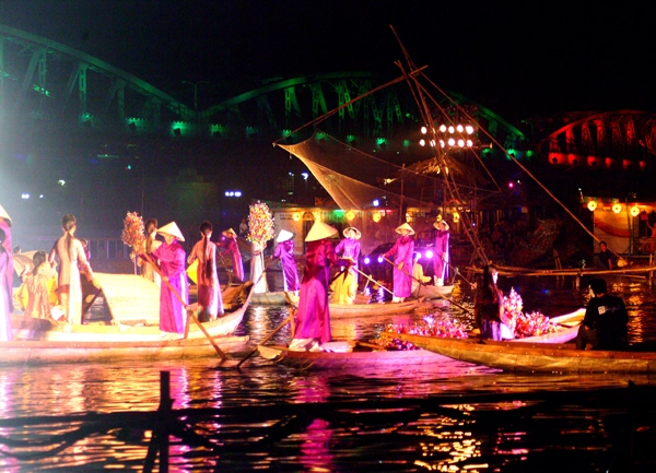 Đây là hình ảnh các nghệ sĩ đang mặc áo dài truyền thống và biểu diễn ca Huế trên một chiếc thuyền rồng rực rỡ ánh đèn giữa dòng sông Hương mênh mông, một trải nghiệm văn hóa không thể bỏ qua để tận hưởng vẻ đẹp của Huế về đêm